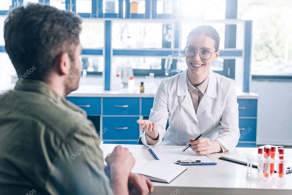 happy allergist looking at bearded man and gesturing on clinic 