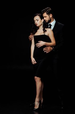 Yakışıklı, sakallı, gözleri kapalı çekici bir kızı kucaklayan siyah bir adam. 