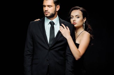 Güzel kadın, siyah giyinmiş sakallı bir adamla dikiliyor. 