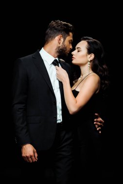 Siyah giysili çekici bir kız, erkek arkadaşının kravatına dokunuyor. 