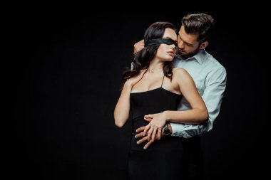 Yakışıklı, sakallı bir adam, gözleri bağlı bir kız arkadaşa bakıyor. 