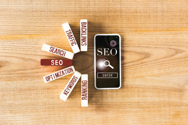 top view of wooden rectangles with concept words of seo and smartphone with seo illustration 