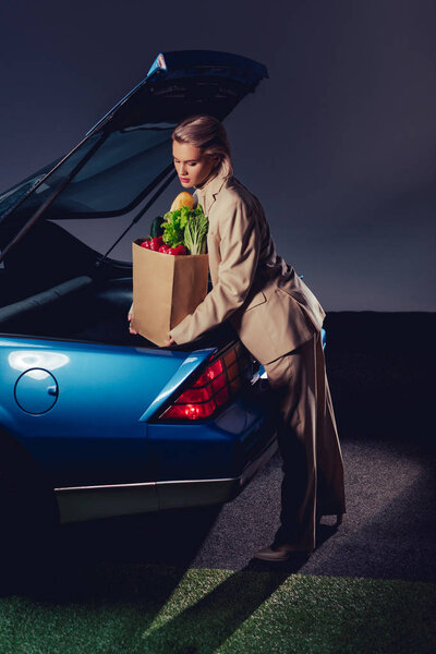 привлекательная и стильная женщина в костюме упаковки бумажный пакет с едой в багажнике
 