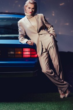 Çekici ve şık takım elbiseli kadın retro arabada yatıyor.