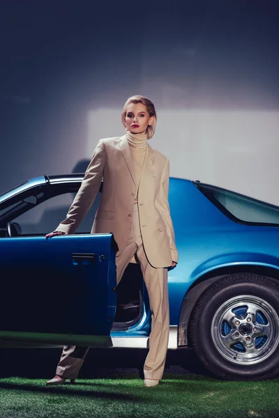 穿着西服的漂亮而时髦的女人站在复古汽车旁边 — 图库照片