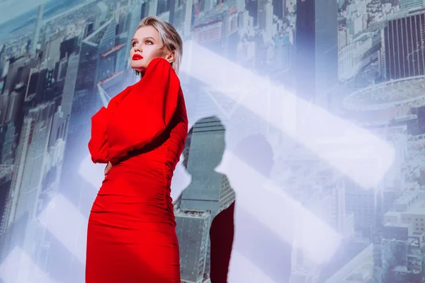 街の背景にある赤いドレスの魅力的でスタイリッシュな女性の低角度ビュー — ストック写真