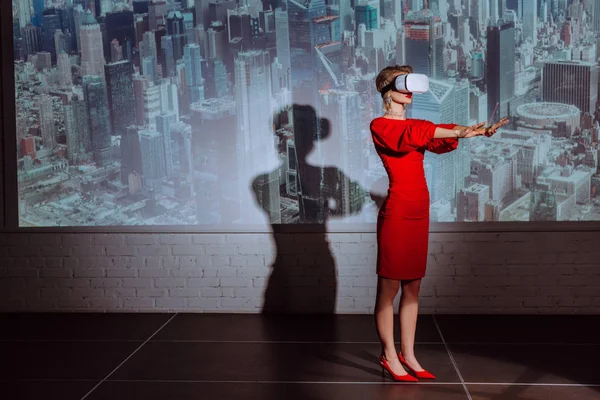 Стильная Женщина Протянутыми Руками Красном Платье Гарнитуре Виртуальной Реальности Фоне — стоковое фото