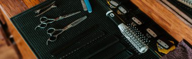 panoramic shot of sharp scissors near hair brush in barbershop  clipart