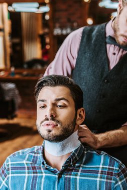 barber fixing collar around neck of handsome bearded man  clipart