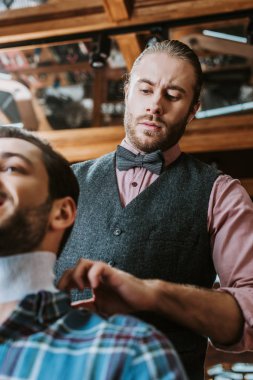 low angle view of barber fixing collar around neck of man  clipart