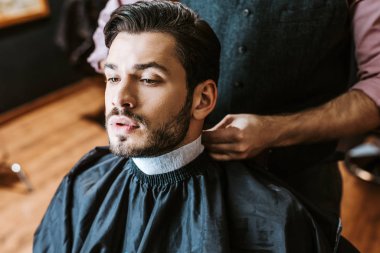 barber fixing collar around neck of man in barbers cape  clipart