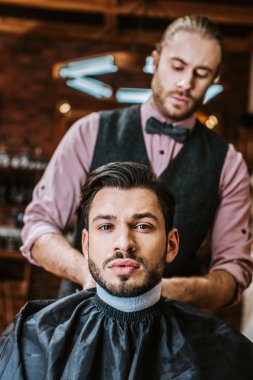 selective focus barber fixing collar around neck of man  clipart