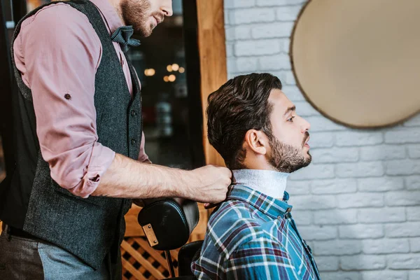 Seitenansicht Des Friseurs Befestigung Kragen Den Hals Des Glücklichen Mannes — Stockfoto