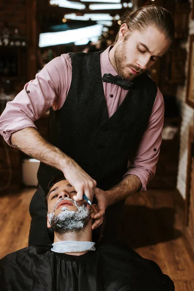 时髦理发师刮胡子男子与剃须霜在脸上 — 图库照片