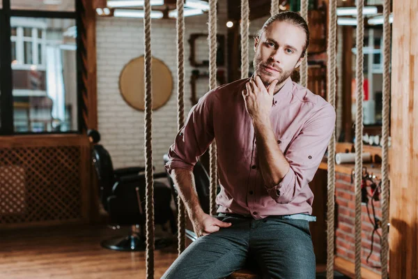 pensive bearded man looking at camera in barbershop