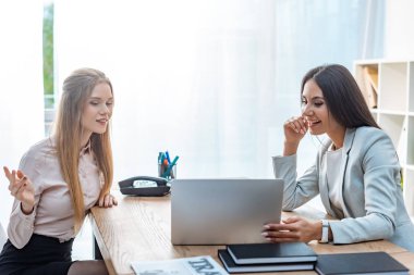 Laptop ekranına bakarken pozitif seyahat acentesi ve istemcisi konuşuyor