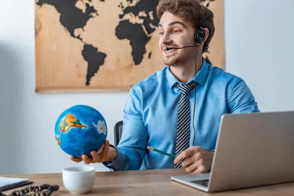 Glimlachende Reisagent Die Wereldbol Vasthoudt Terwijl Hij Werkplek Zit — Stockfoto