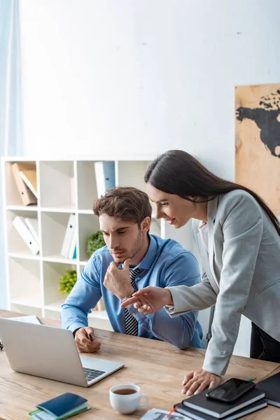 Attraktives Reisebüro Zeigt Mit Dem Finger Auf Laptop Neben Kollege — Stockfoto