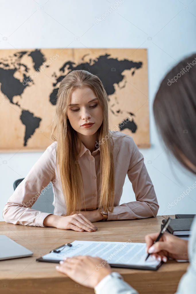 cropped view of client signing contract near attentive travel agent