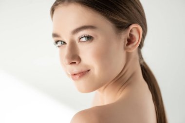 Güzel, çıplak, gülümseyen kadın beyaz poz veriyor.