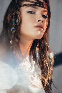 Saç stili örgülü kendine güvenen boho kızı. Gri üzerine mercekli poz veriyor. 