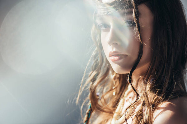 beautiful boho girl with braids in hairstyle posing on grey with lens flares 