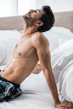 Yakışıklı ve seksi çift ırklı adam sabahları yatakta oturuyor. 