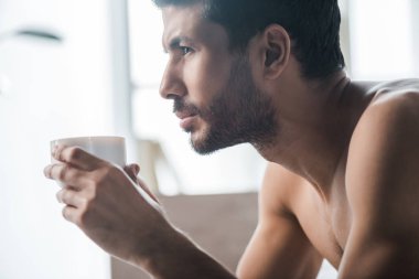 Sabahları elinde kahve tutan iki ırklı yakışıklı adamın yan görüntüsü. 