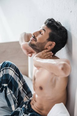 Yakışıklı ve seksi çift ırklı bir adam, sabahleyin elleri başının üstünde. 