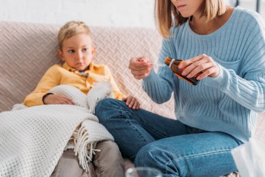 Annesinin hasta oğlunun yanında otururken kaşığa öksürük şurubu döktüğünü gördüm.