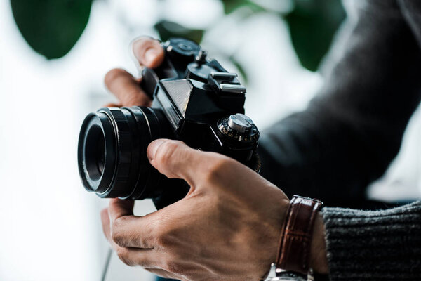 cropped view of bi-racial man holding digital camera in apartment 