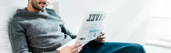 Panoramiczne Ujęcie Uśmiechniętego Rasowego Mężczyzny Czytającego Gazety Podróżami Literowymi — Zdjęcie stockowe