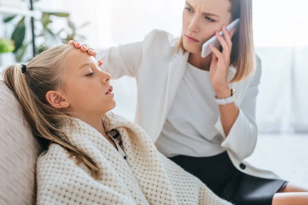 Caring Mother Touching Forehead Diseased Daughter While Talking Smartphone — Stock Photo, Image