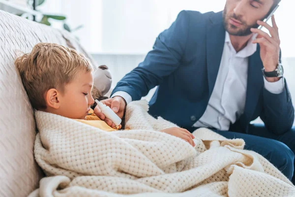 Attentive Father Holding Nasal Spray Sick Son While Talking Smartphone — Stock Photo, Image