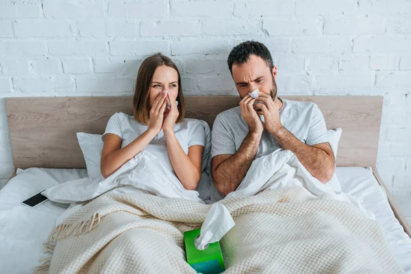 生病的丈夫和妻子躺在床上打喷嚏 — 免费的图库照片
