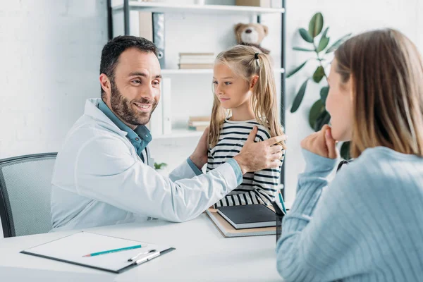 Glimlachende Arts Kijken Naar Moeder Tijdens Het Onderzoeken Van Kind — Stockfoto