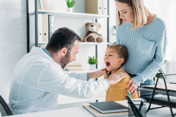 Uważny Pediatra Badający Gardło Chłopca Pobliżu Matki — Zdjęcie stockowe