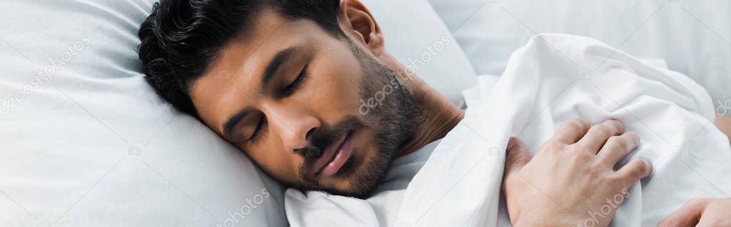 panoramic shot of handsome bi-racial man sleeping in bed in morning 