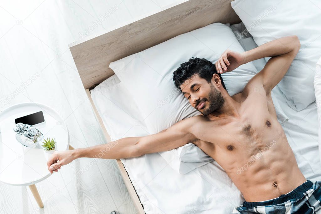 top view of handsome bi-racial man waking up and stretching in morning 