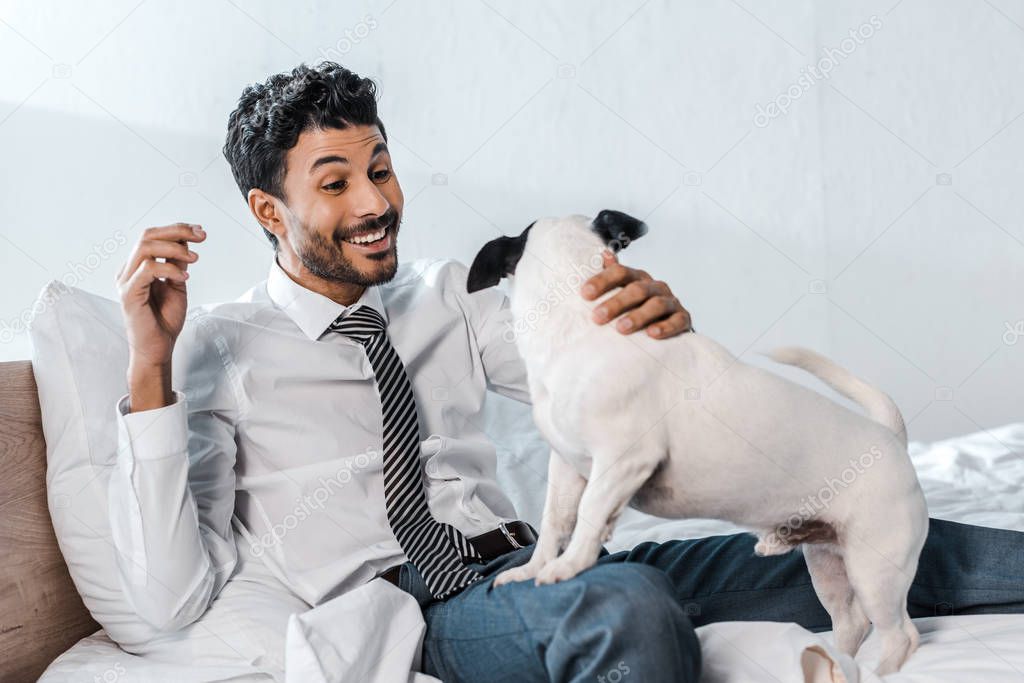 smiling bi-racial businessman holding Jack Russell Terrier in morning at home 