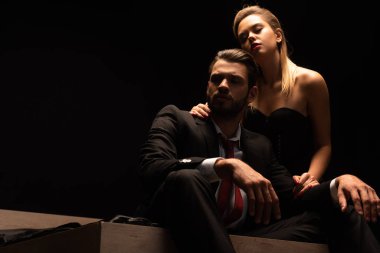 Güzel, zarif, seksi çift karanlık odada yatakta oturuyor.