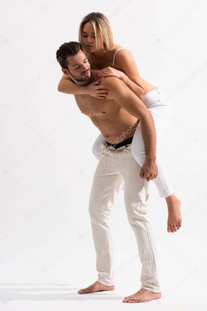 happy sexy couple in white jeans piggybacking on white