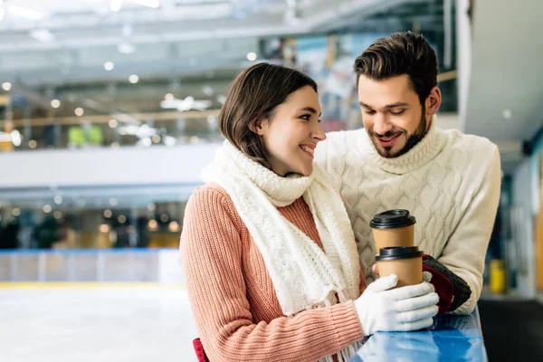 スケートリンクに行くためにコーヒーを持って笑っているカップル — ストック写真