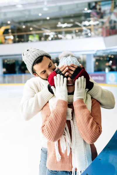 Fröhlicher Mann Drückt Frau Die Augen Auf Eisbahn Für Eine — Stockfoto