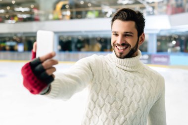 Neşeli adam paten sahasında akıllı telefondan video görüşmesi yapıyor.