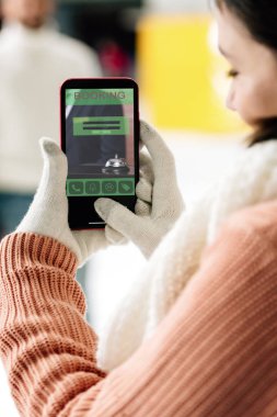 Kyiv, Ukrayna - 15 Kasım 2019: Eldivenli kadın ekranda akıllı telefon uygulaması ile görüntüsü kesilmiş