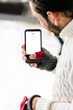 Kyiv, Ukrayna - 15 Kasım 2019: Eldivenli bir adamın Skype uygulamalı akıllı telefonu ekranda, buz pateni pistinde görüntüsü