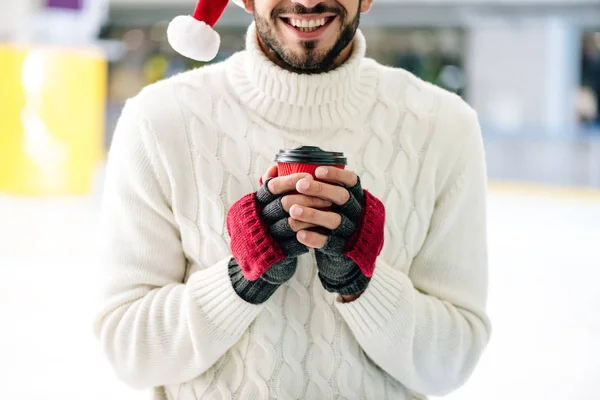 看到戴着圣诞礼帽的快乐男人拿着咖啡去溜冰场 — 图库照片