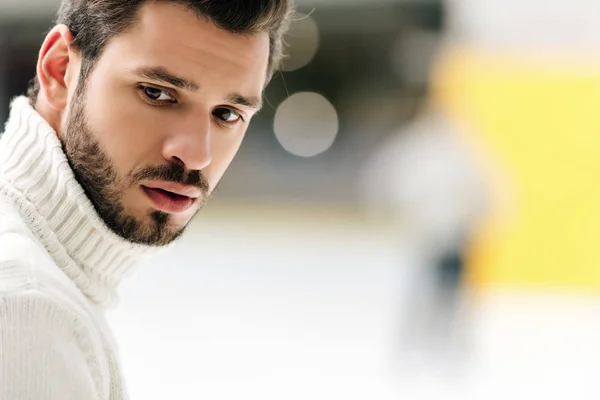 portrait of handsome bearded man in sweater on skating rink