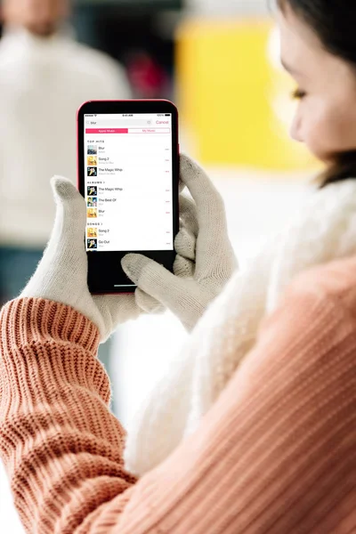 Kyiv, Ukrayna - 15 Kasım 2019: Elmas müzik uygulamalı akıllı telefon tutan kadın görüntüsü ekrana yansıdı